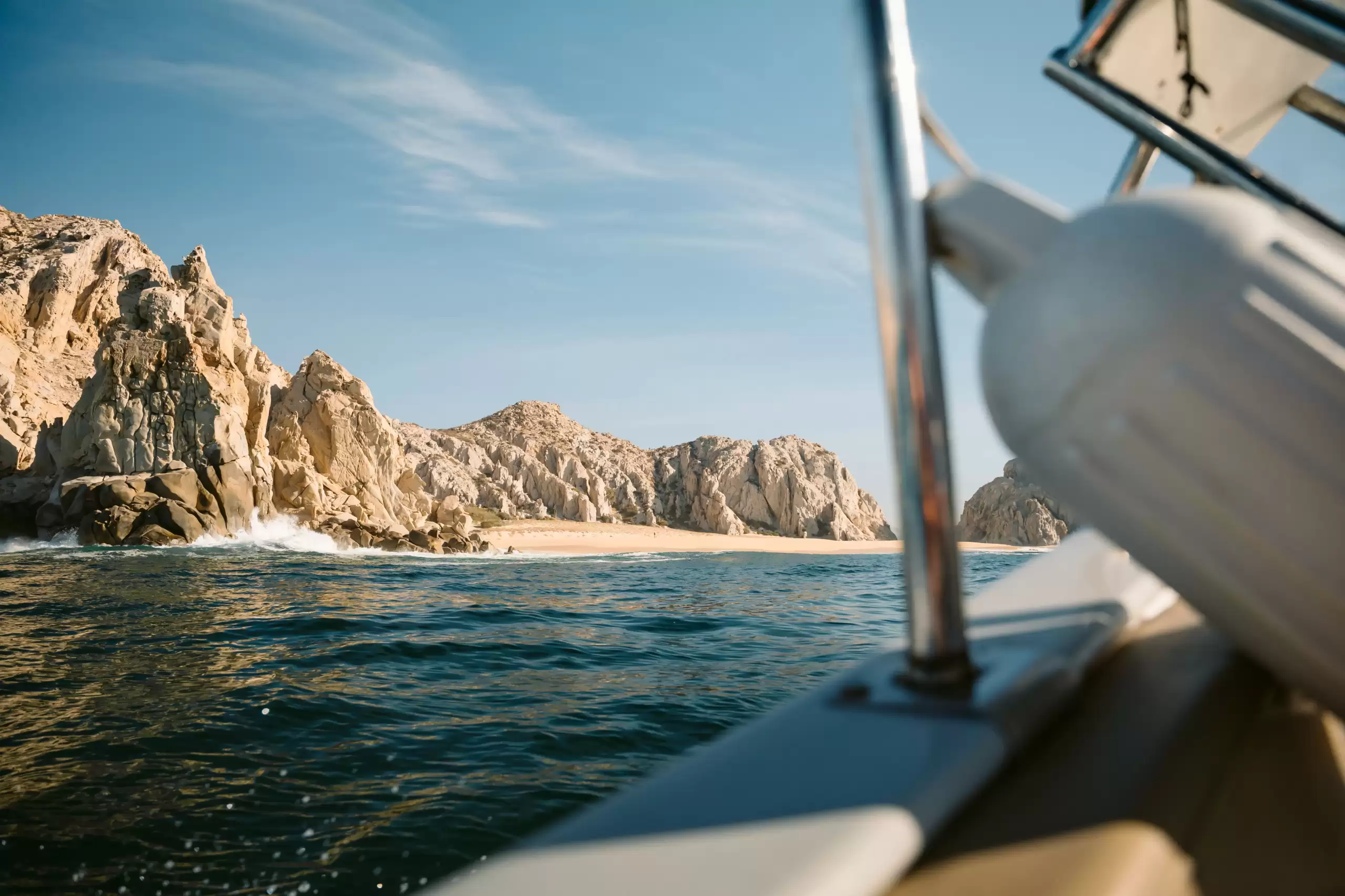 Catamaran rental in Los Cabos cruising near rocky beaches and the Cabo San Lucas coastline, ideal for private sightseeing and coastal trips.